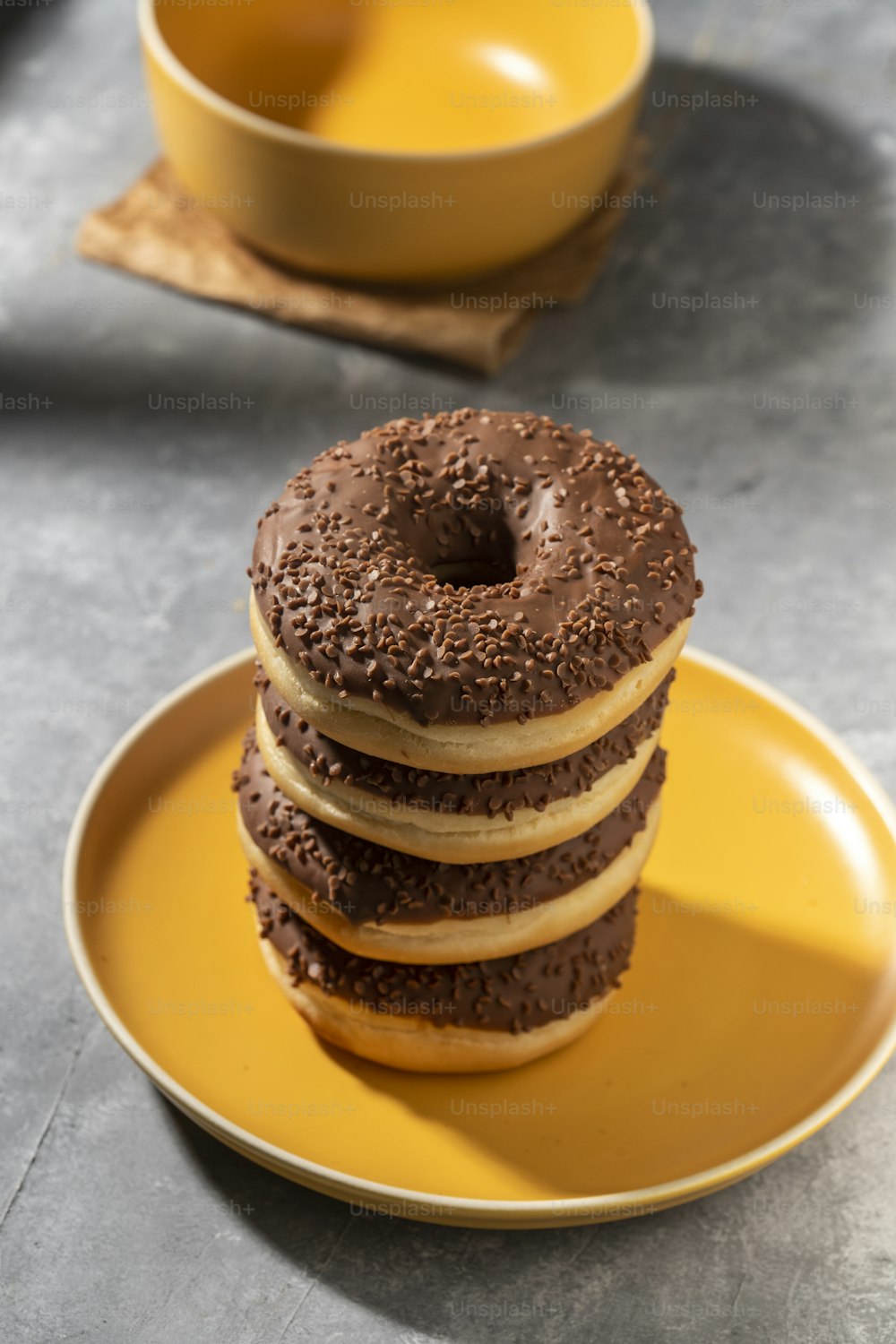 a stack of chocolate donuts sitting on top of a yellow plate