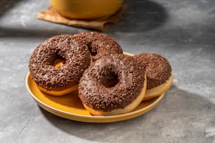 three chocolate donuts sitting on a yellow plate