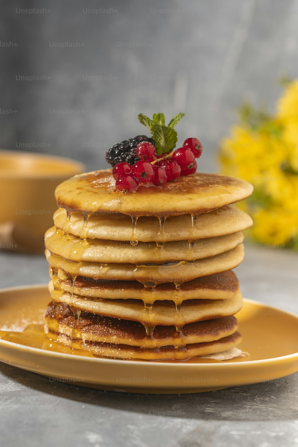 a stack of pancakes topped with berries and syrup