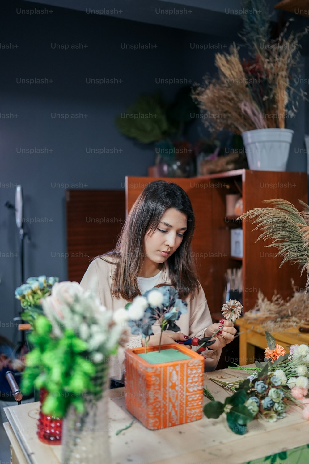 a woman sitting at a table working on a flower arrangement