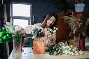 a woman arranging flowers in a vase on a table