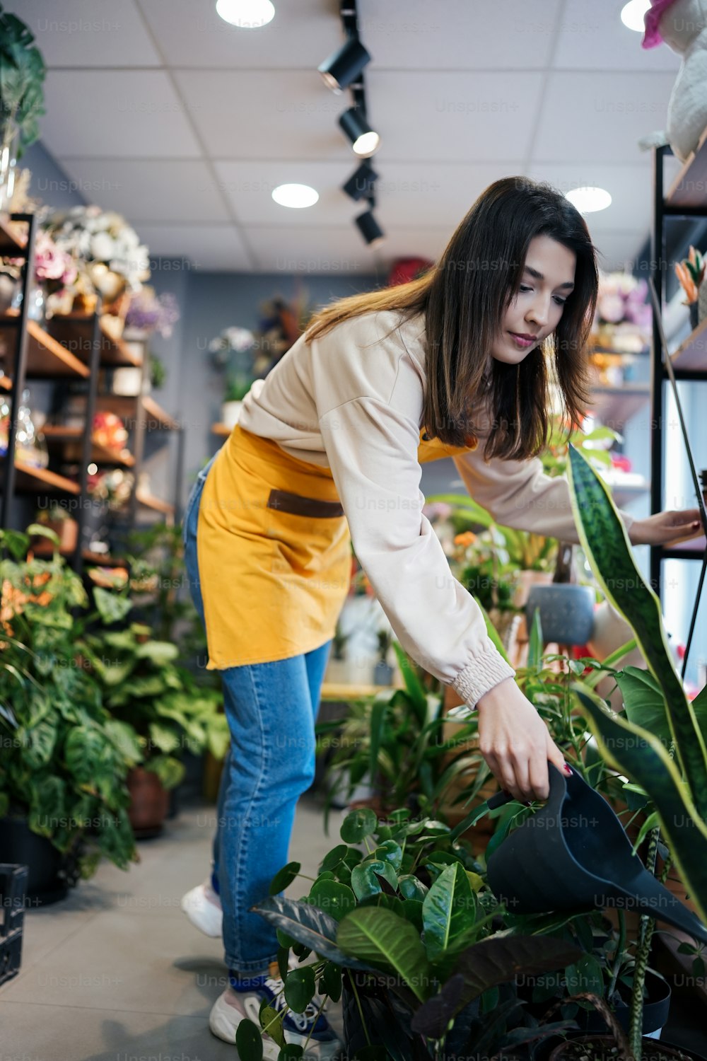 a woman watering plants in a flower shop