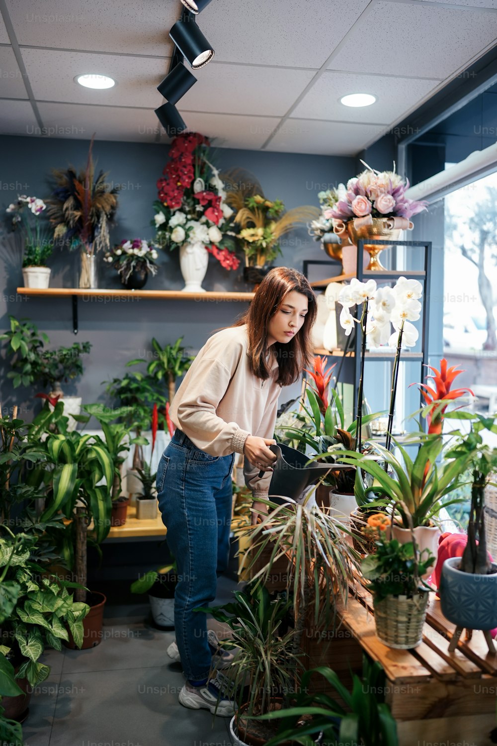 Una mujer de pie en una habitación llena de plantas en macetas