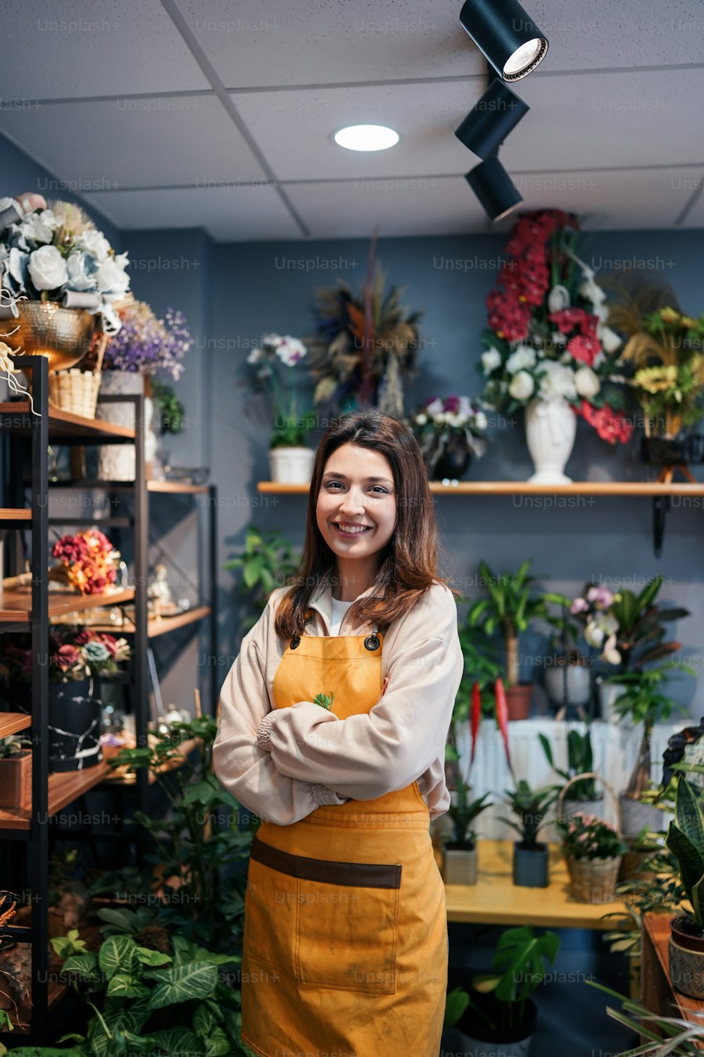 Una donna in piedi in un negozio di fiori con le braccia incrociate