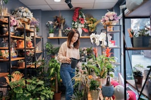 a woman standing in a room filled with potted plants