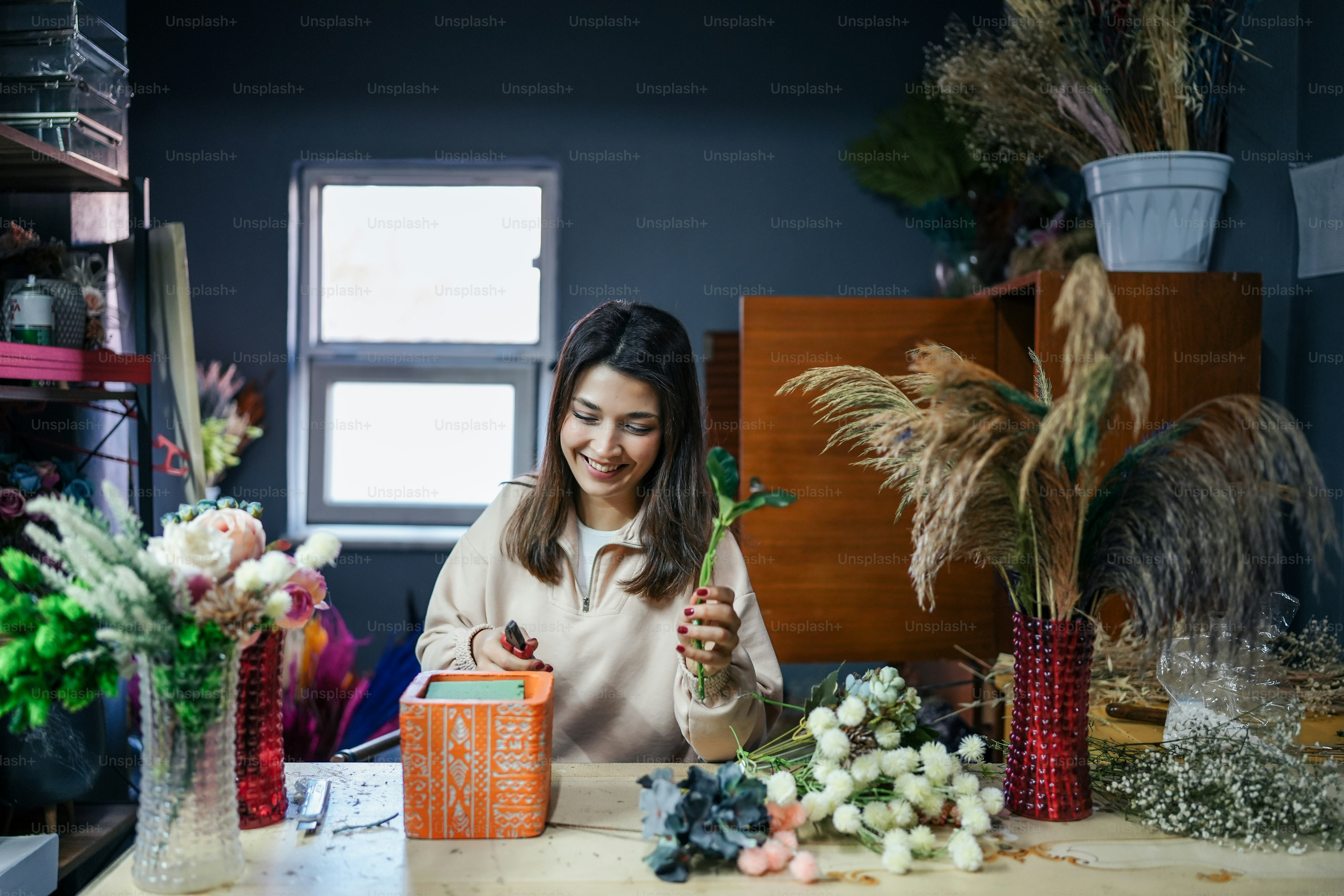 Eine Frau sitzt an einem Tisch umgeben von Blumen