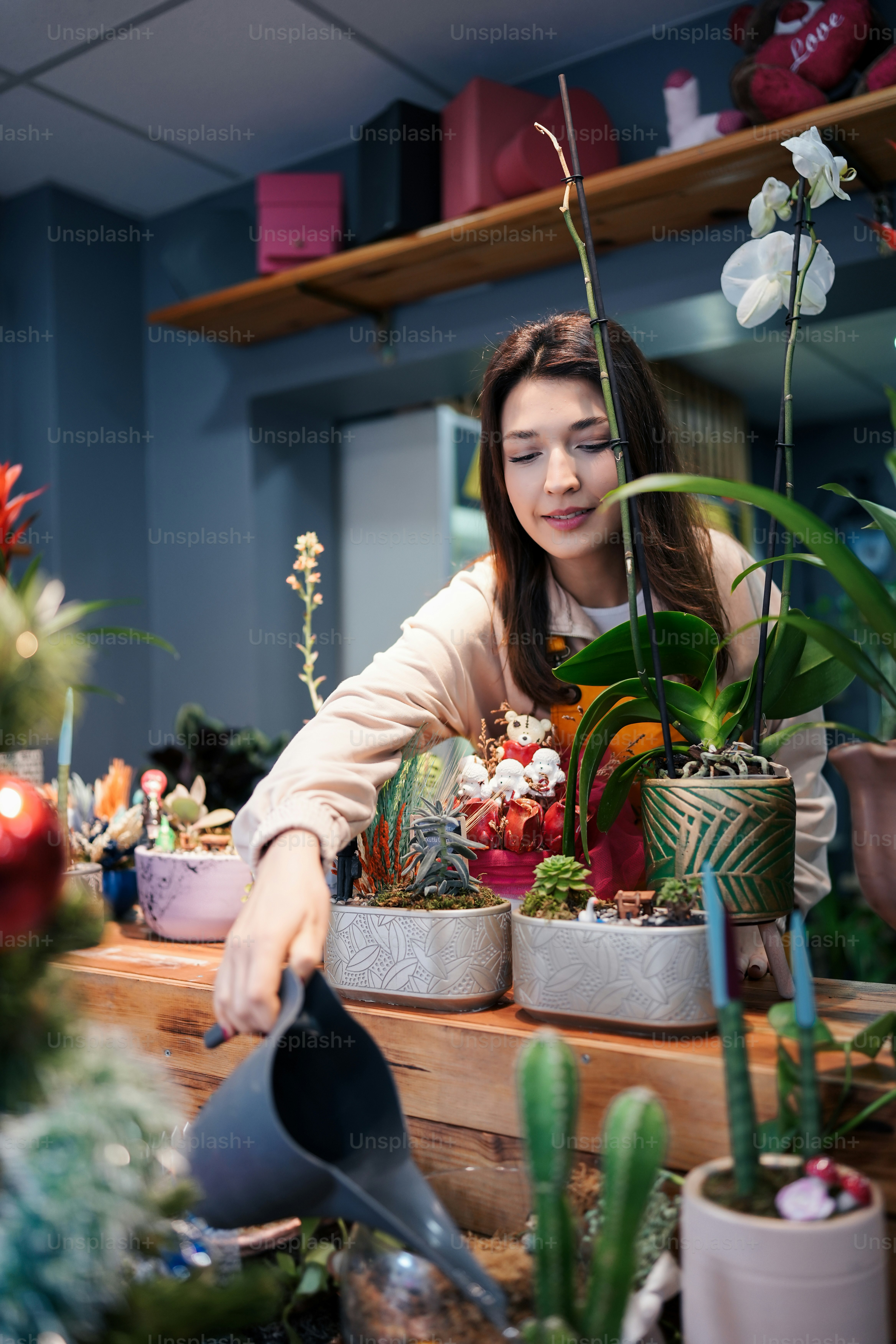 Eine Frau gießt Pflanzen in einem Blumenladen