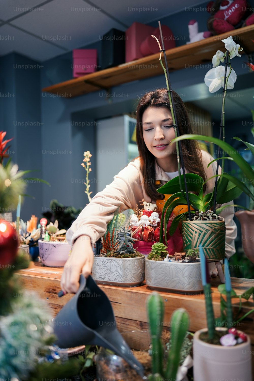Una mujer regando plantas en una floristería