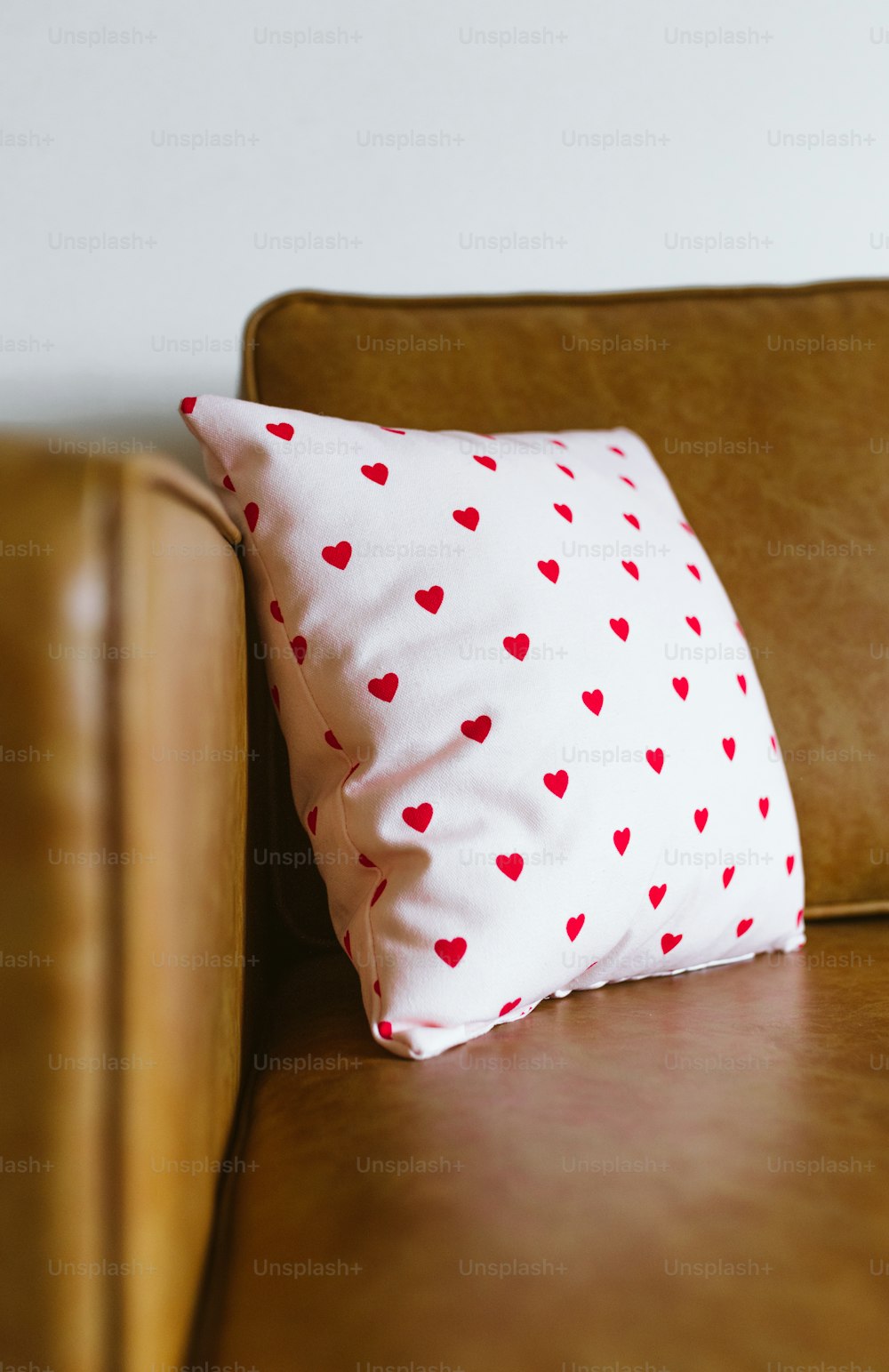 Un divano marrone con un cuscino a cuore rosso su di esso