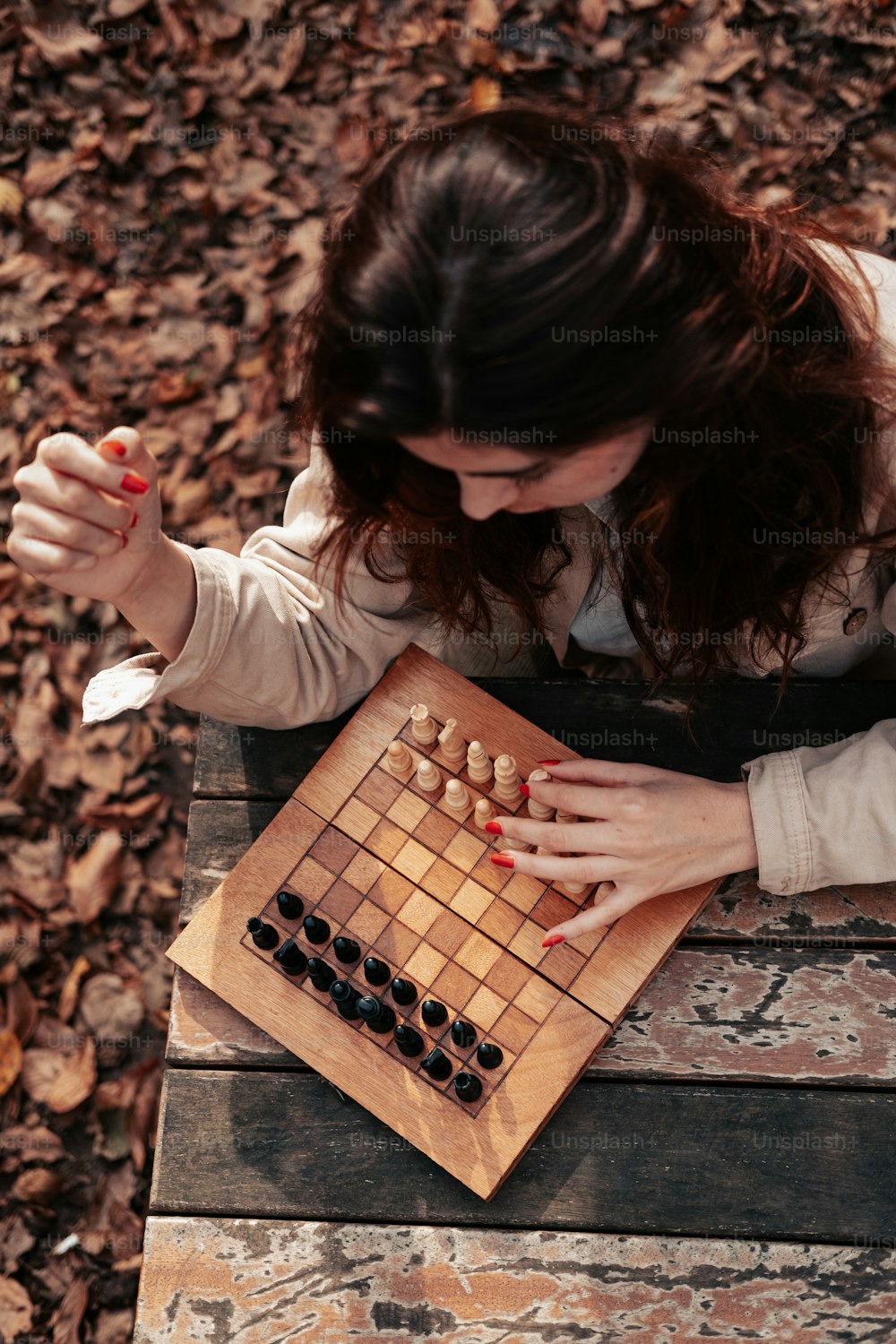 a woman playing a game of chess on a park bench