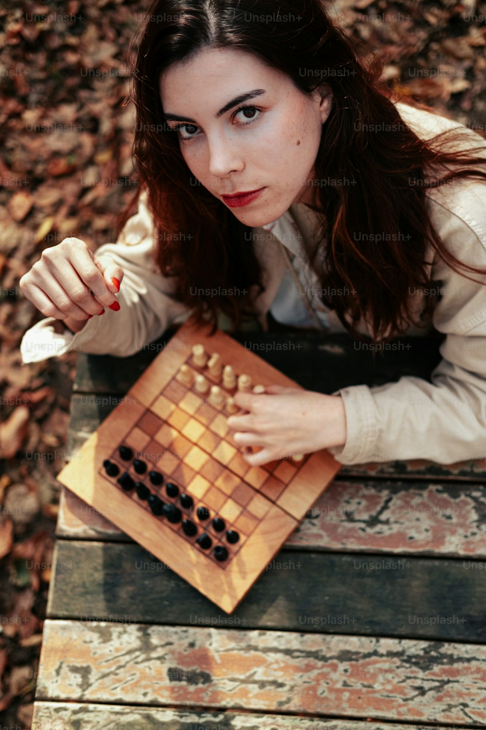 uma mulher sentada em uma mesa com um tabuleiro de xadrez