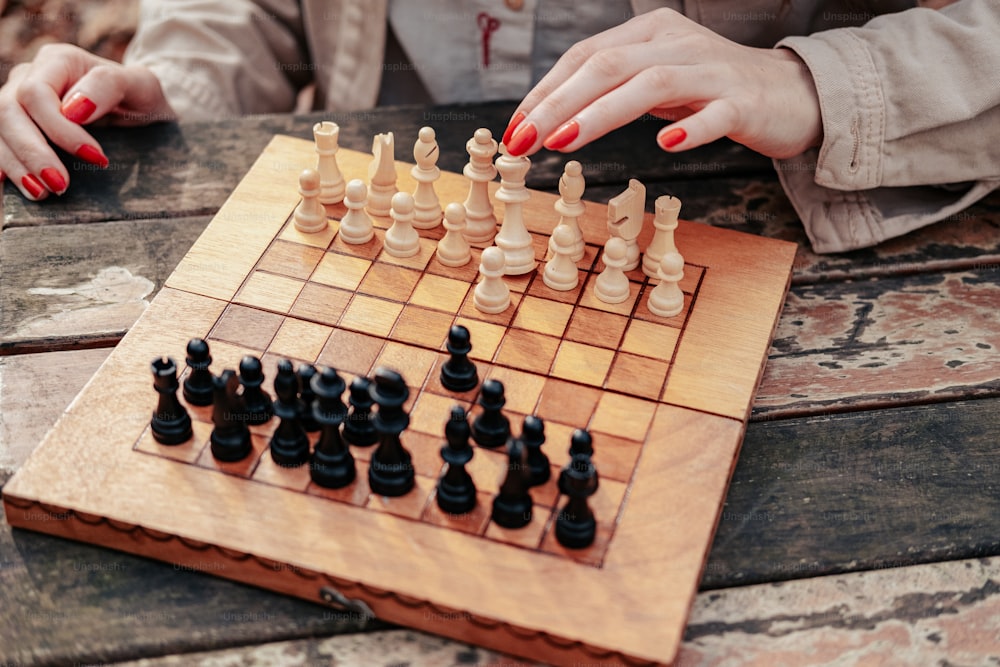 uma mulher que joga um jogo de xadrez em uma mesa de madeira