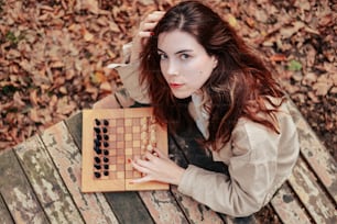 a woman sitting on a bench holding a board with a game on it