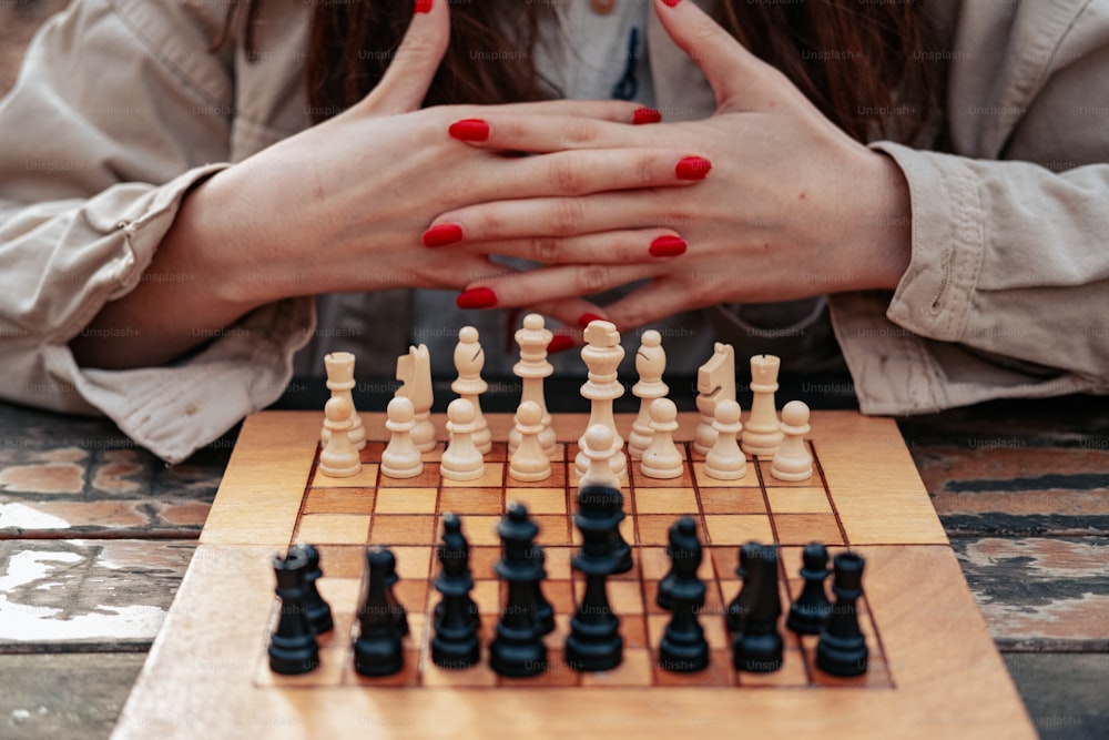 a woman sitting at a table with her hands on a chess board