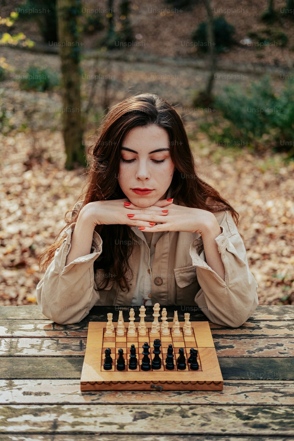 a woman sitting at a table with a chess set