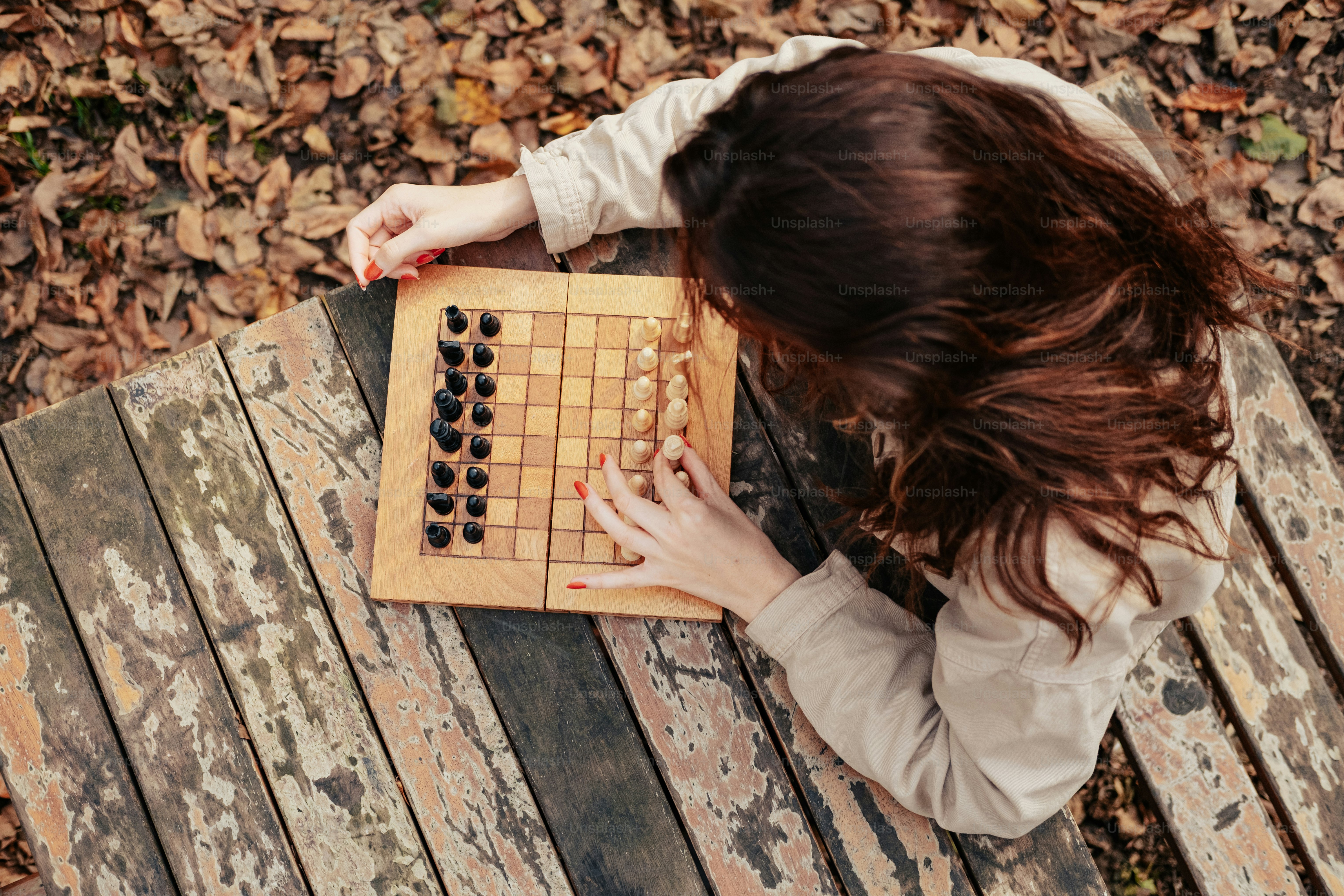 a woman playing a game of chess on a bench