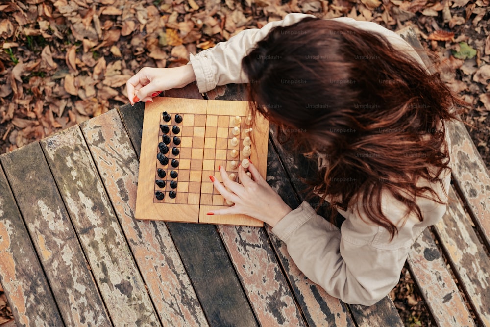 a woman playing a game of chess on a bench