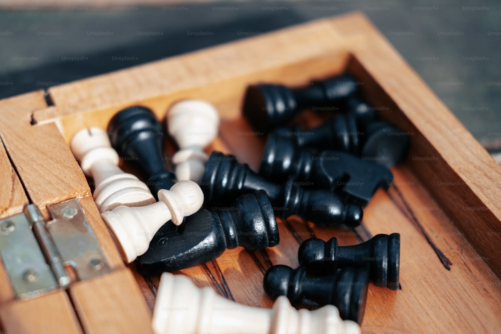 uma caixa de madeira cheia de peças de xadrez preto e branco