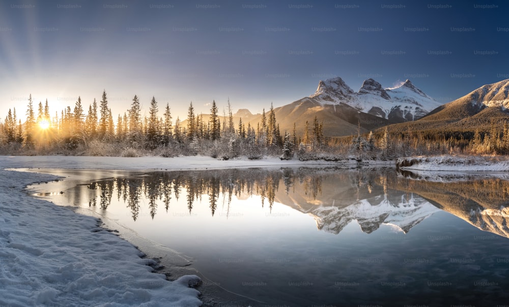 un lago rodeado de árboles cubiertos de nieve y montañas