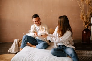 a man and woman sitting on a bed with a cake