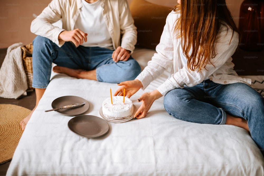 um homem e uma mulher sentados em uma cama com um bolo