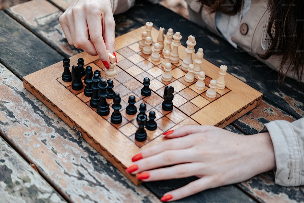 a woman playing a game of chess on a wooden table