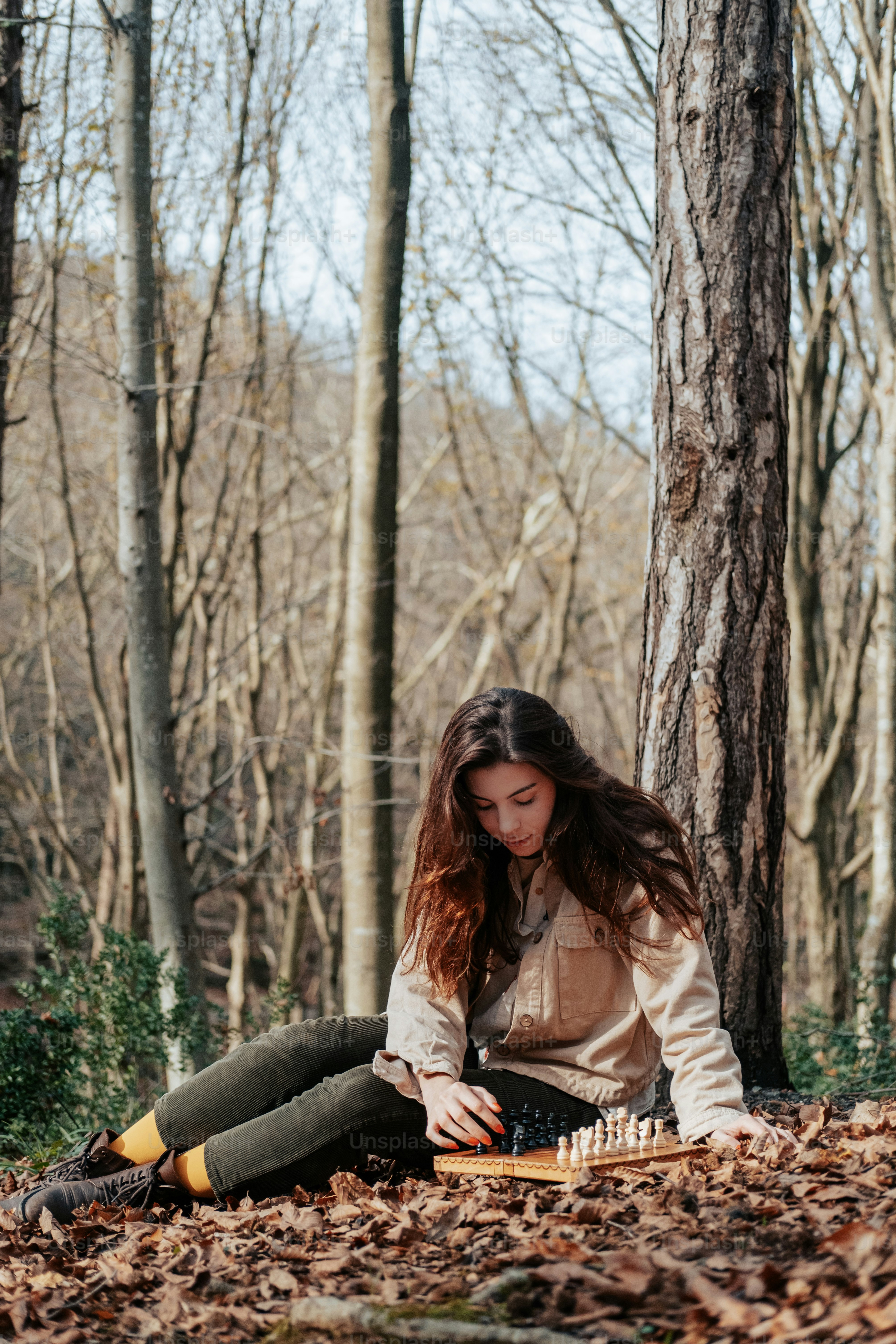 A woman sitting on the ground in the woods photo – Girl in the forest ...