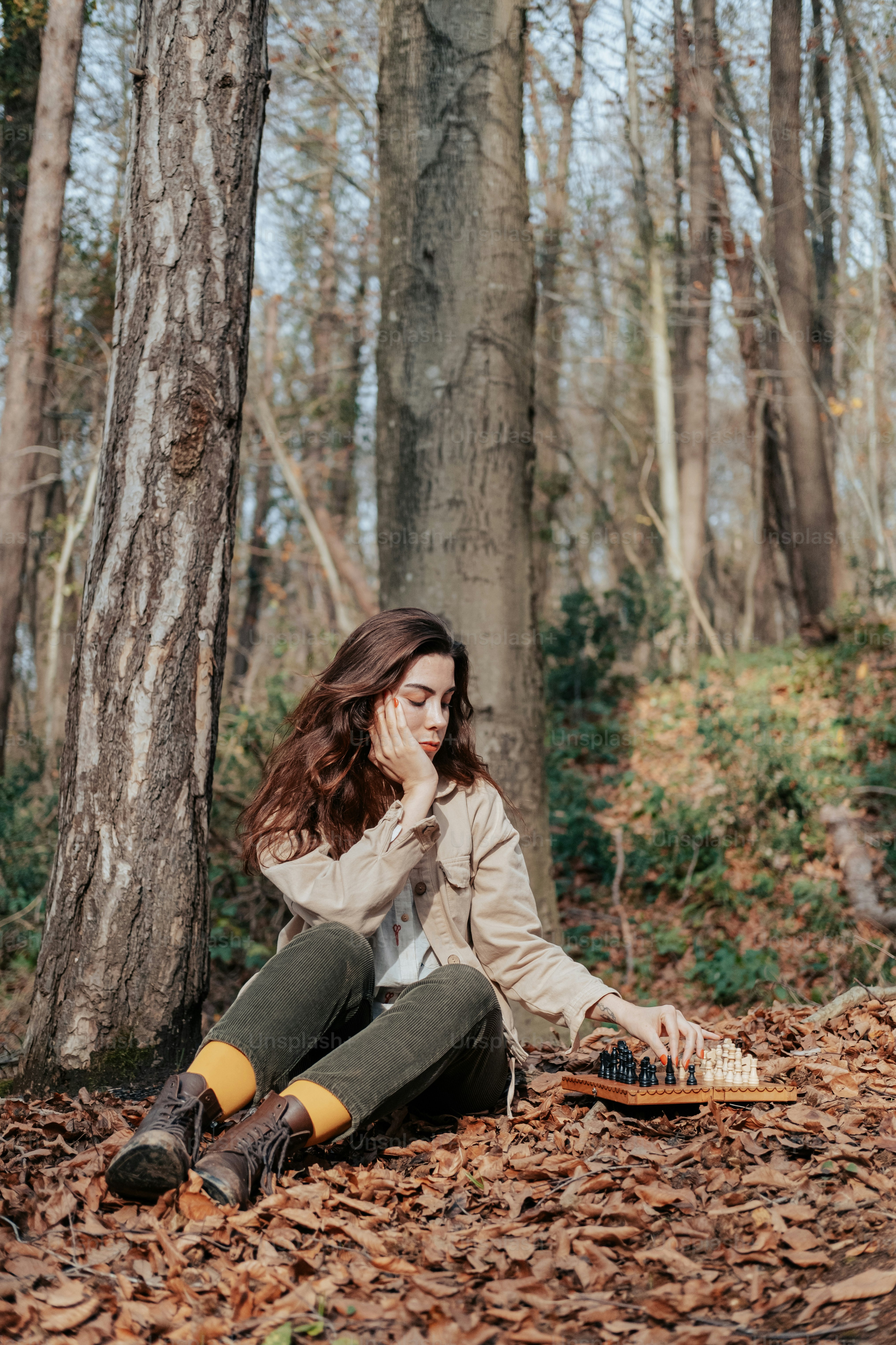 a woman sitting on the ground in the woods