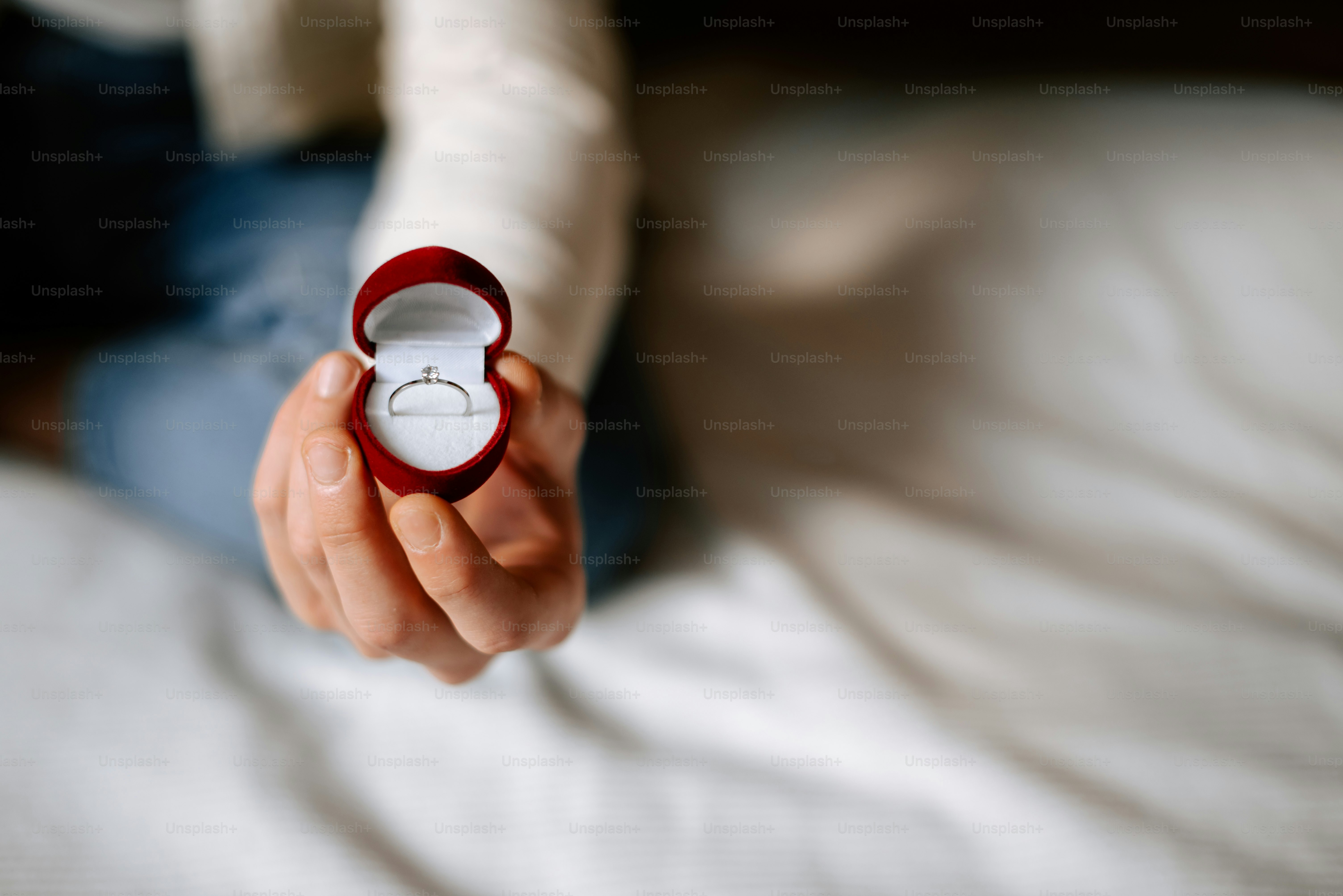 a woman holding a ring with a diamond in it