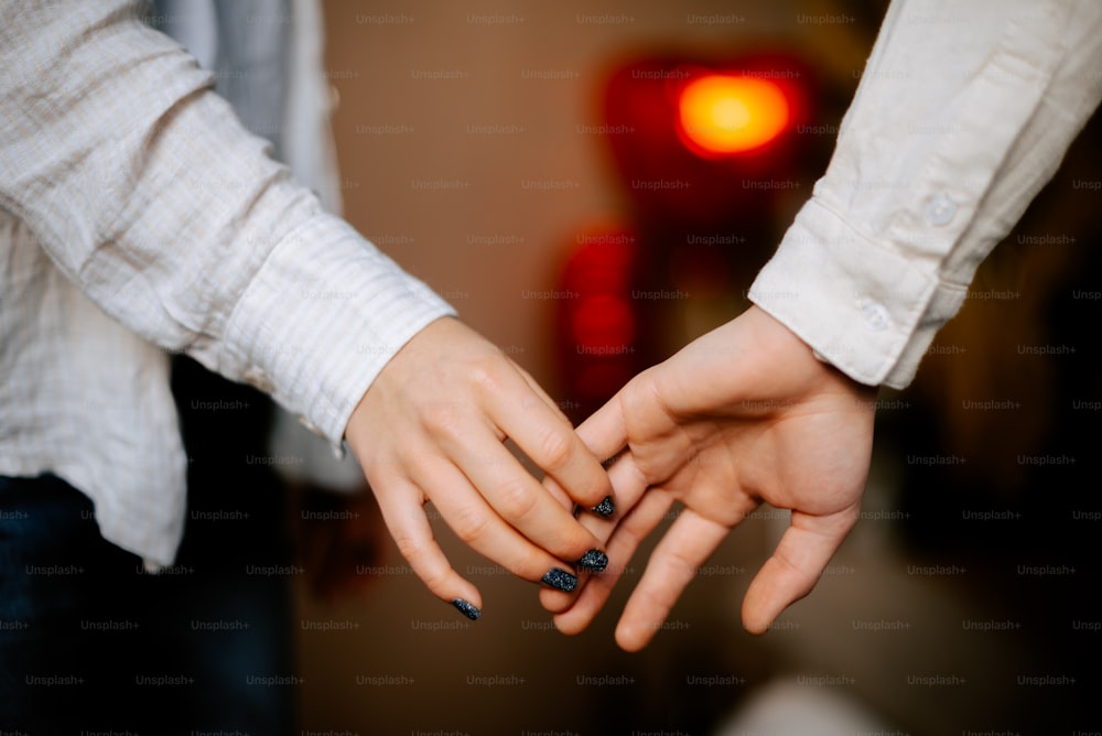 two people holding hands in front of a red light
