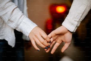 two people holding hands in front of a red light