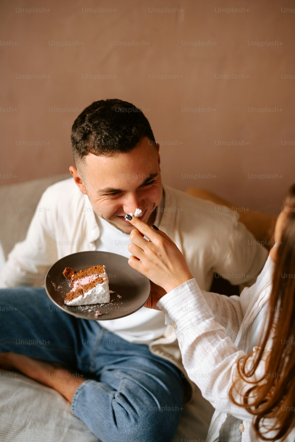 a man and woman sitting on a bed eating cake