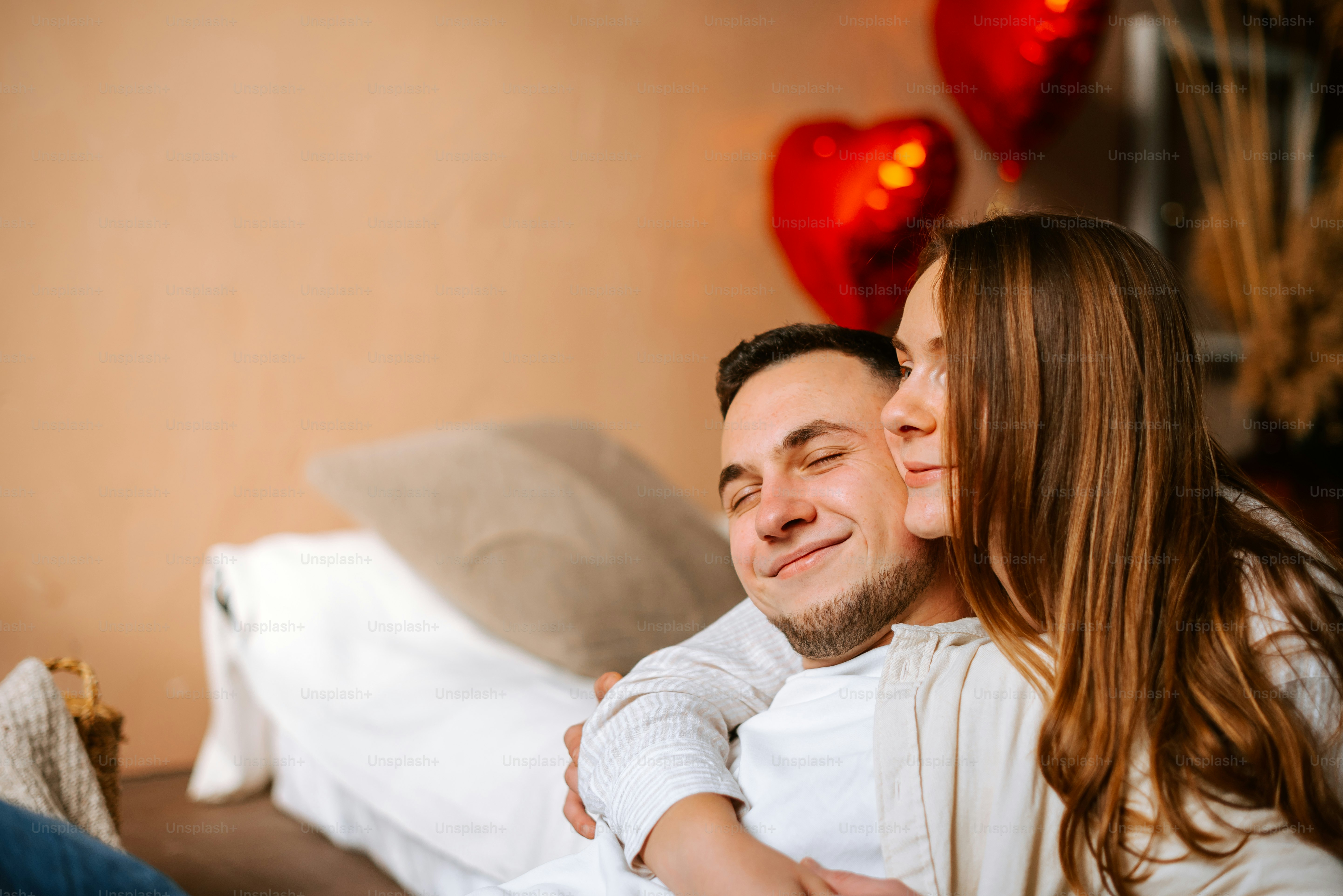a man and a woman cuddling on a bed