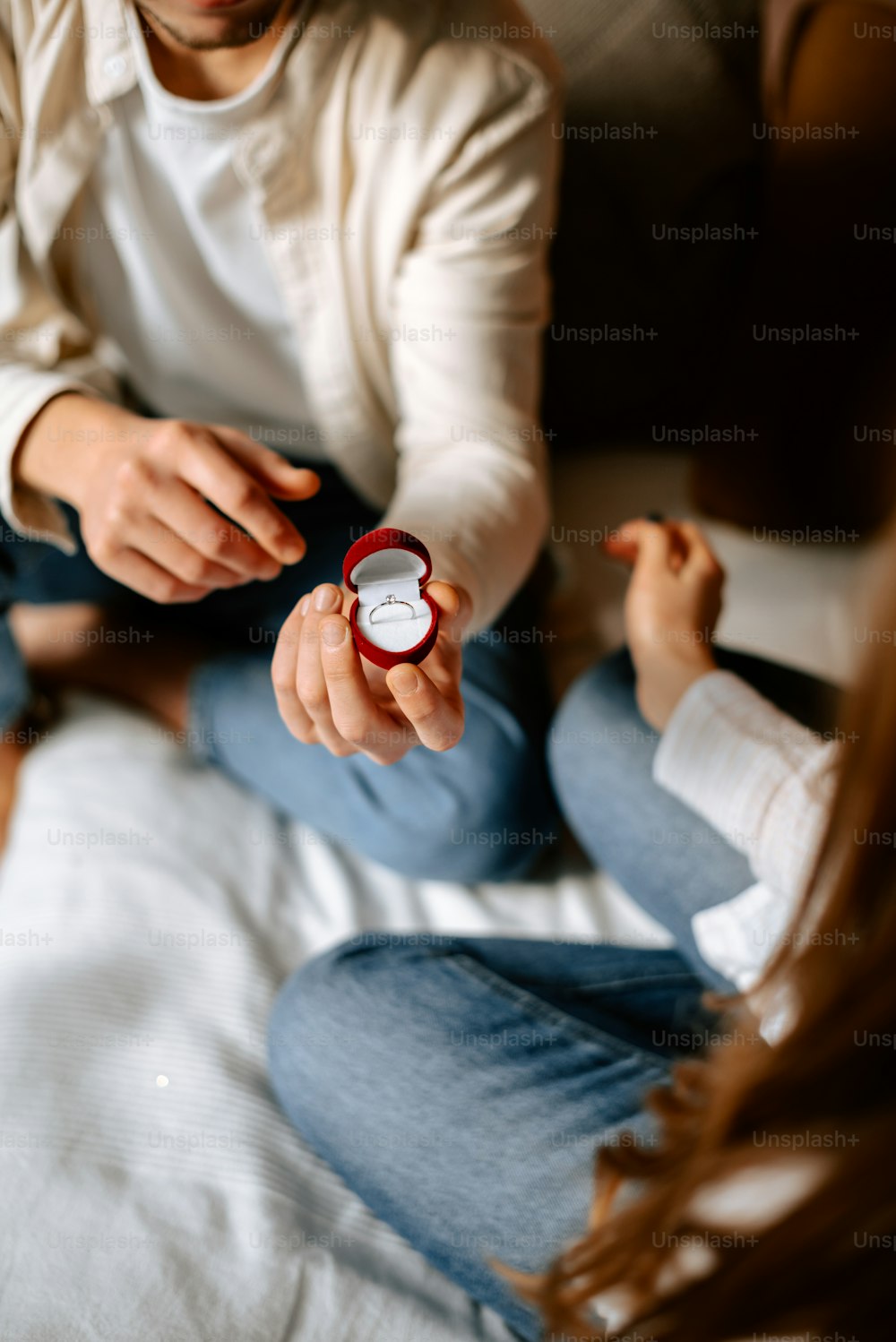 Ein Mann, der eine Uhr hält, während er auf einem Bett sitzt