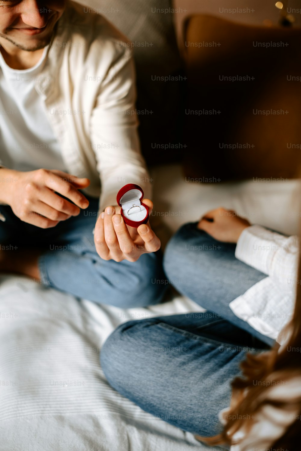 a man sitting on a bed holding a watch