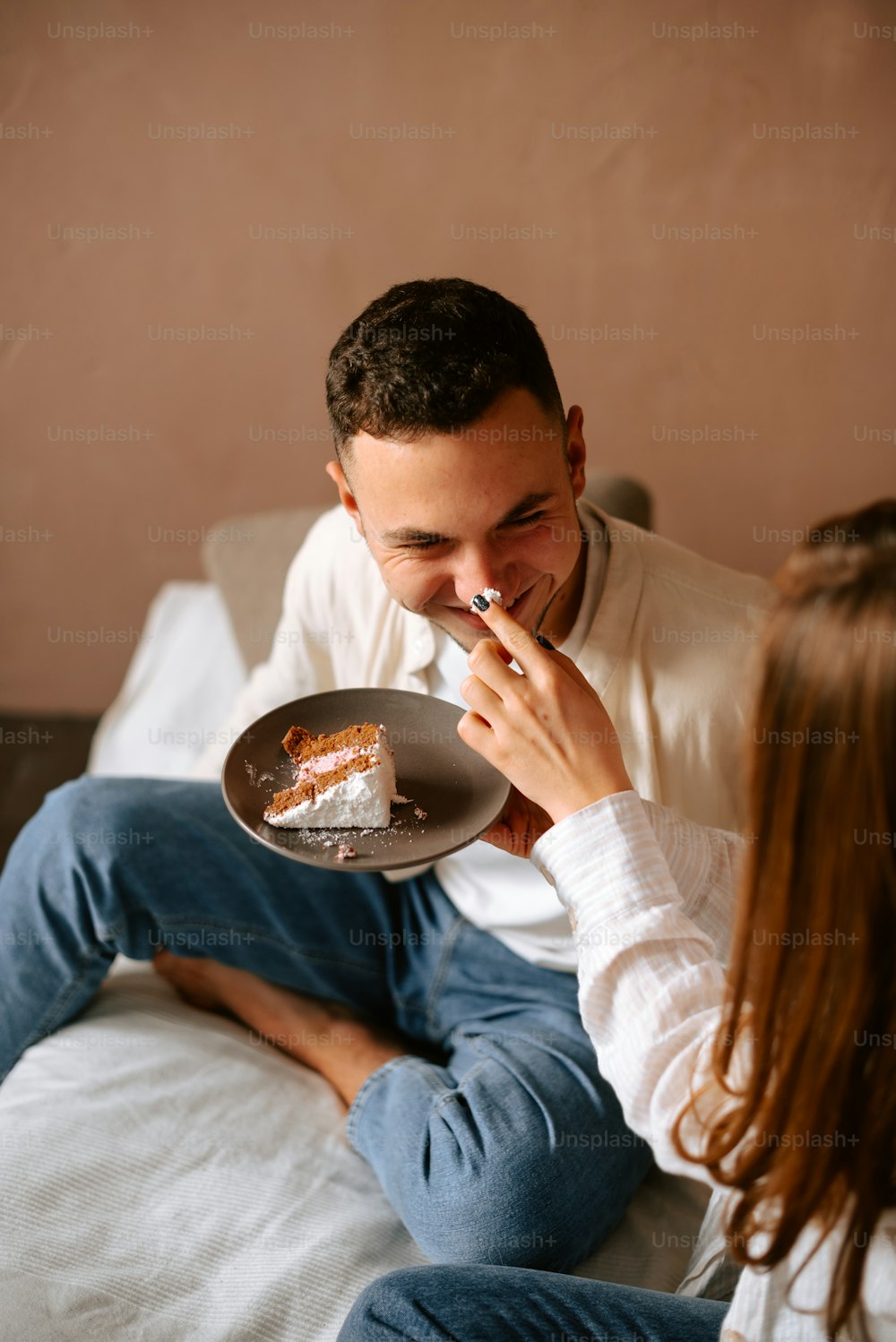 a man and woman sitting on a bed eating cake