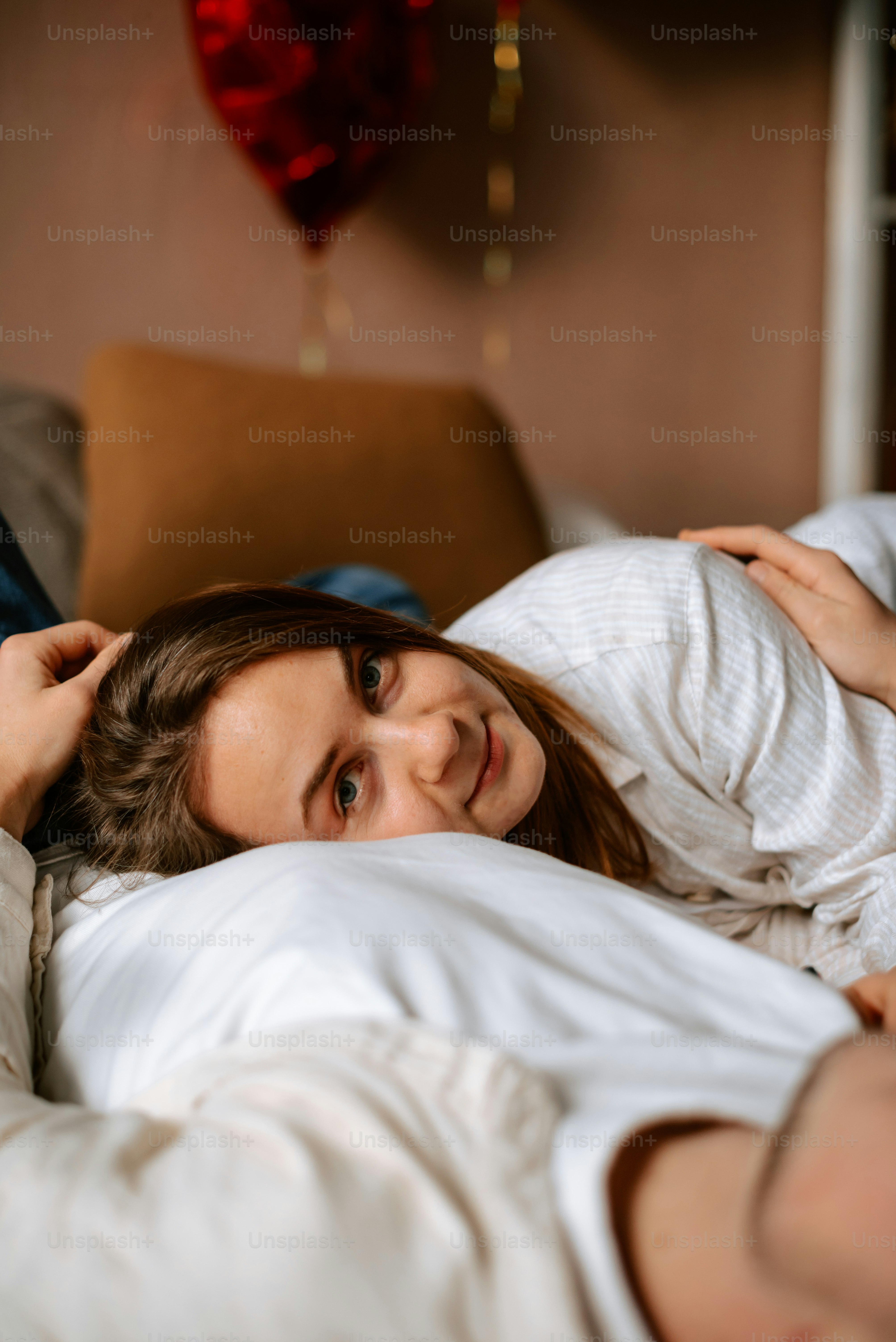 a woman laying in bed with a heart hanging above her head