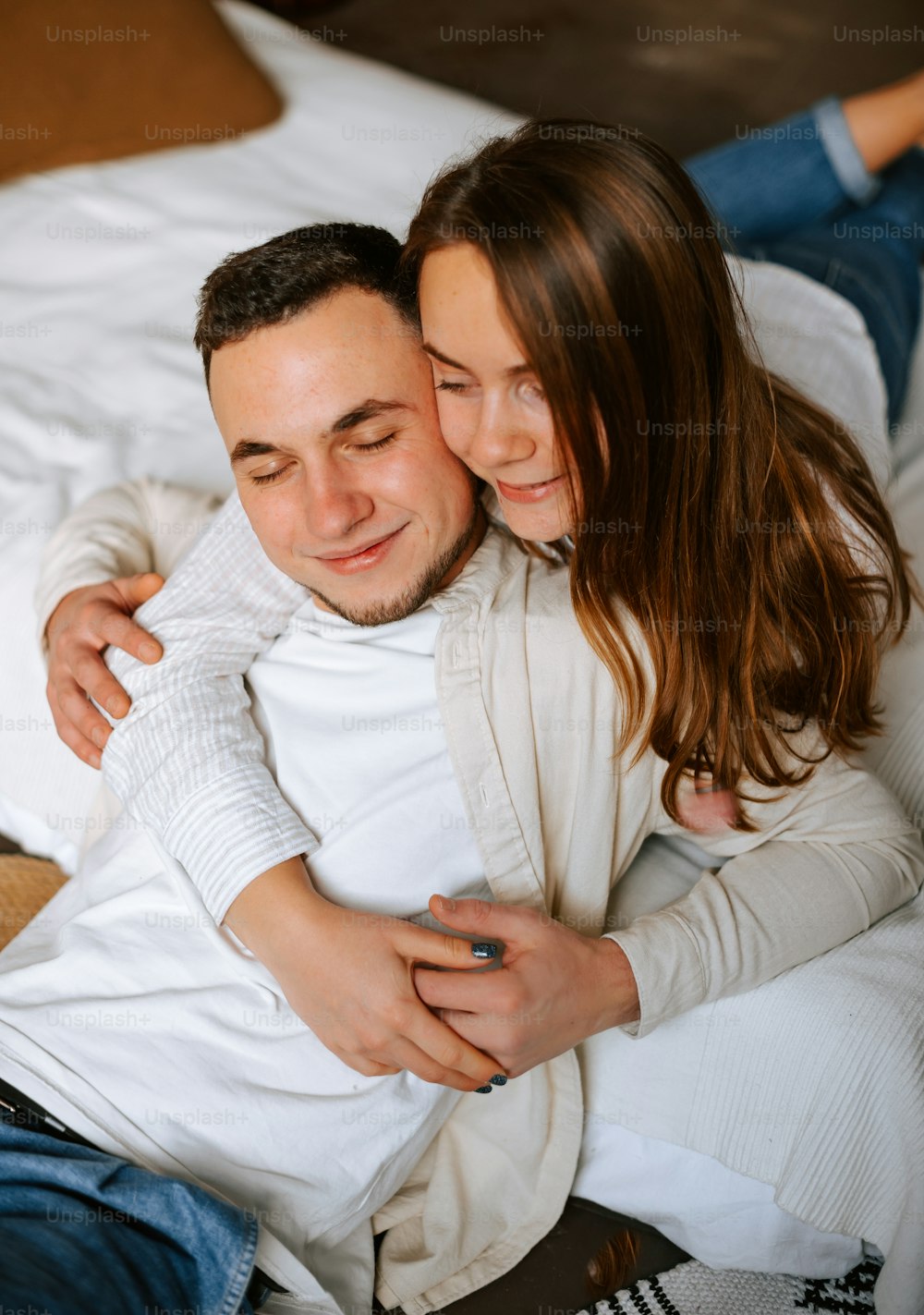 a man and a woman cuddling on a bed