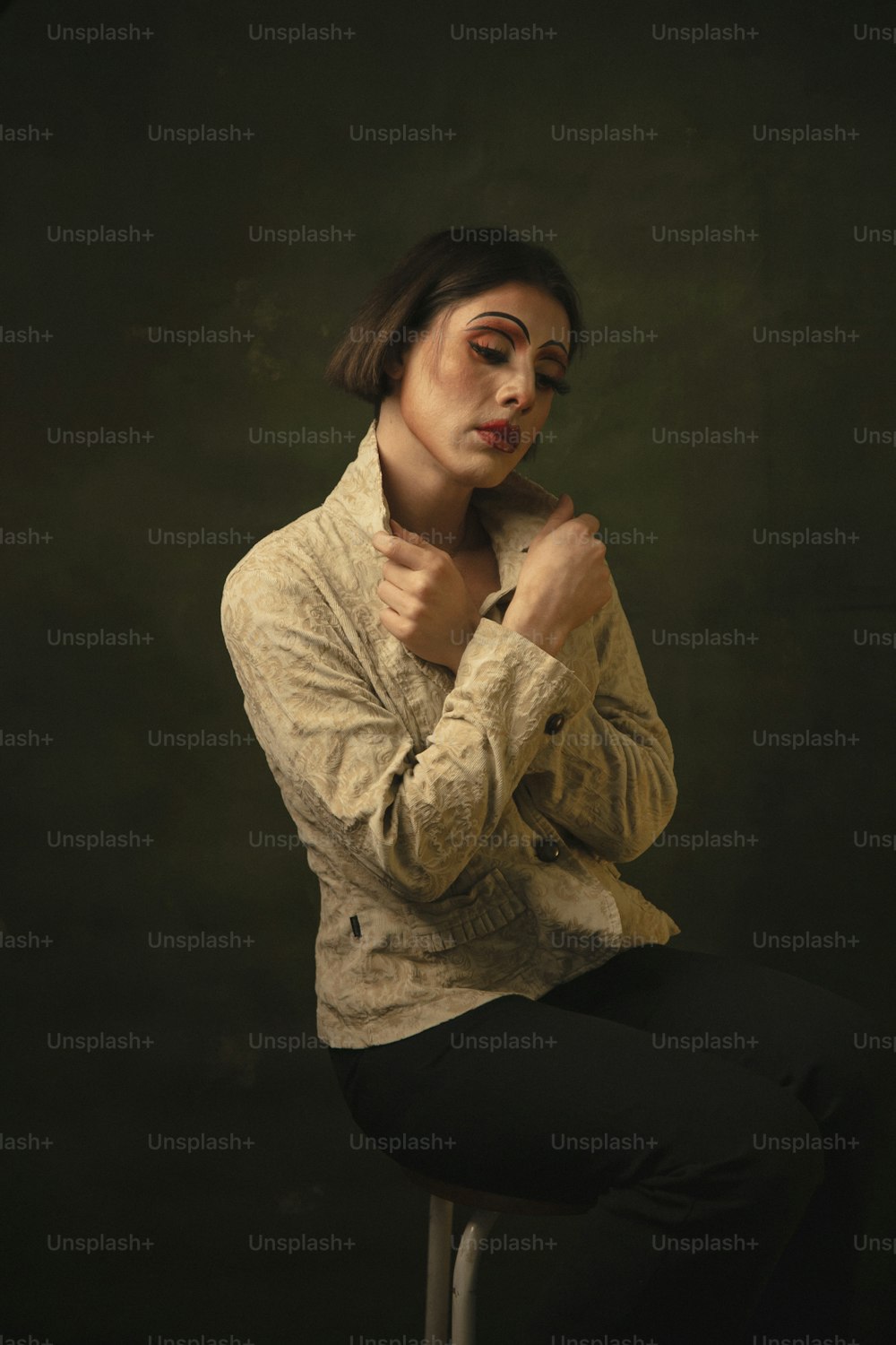 Una mujer sentada en un taburete con las manos en el pecho