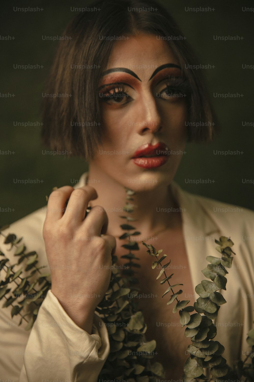 eine Frau mit Make-up im Gesicht und Blättern um den Hals