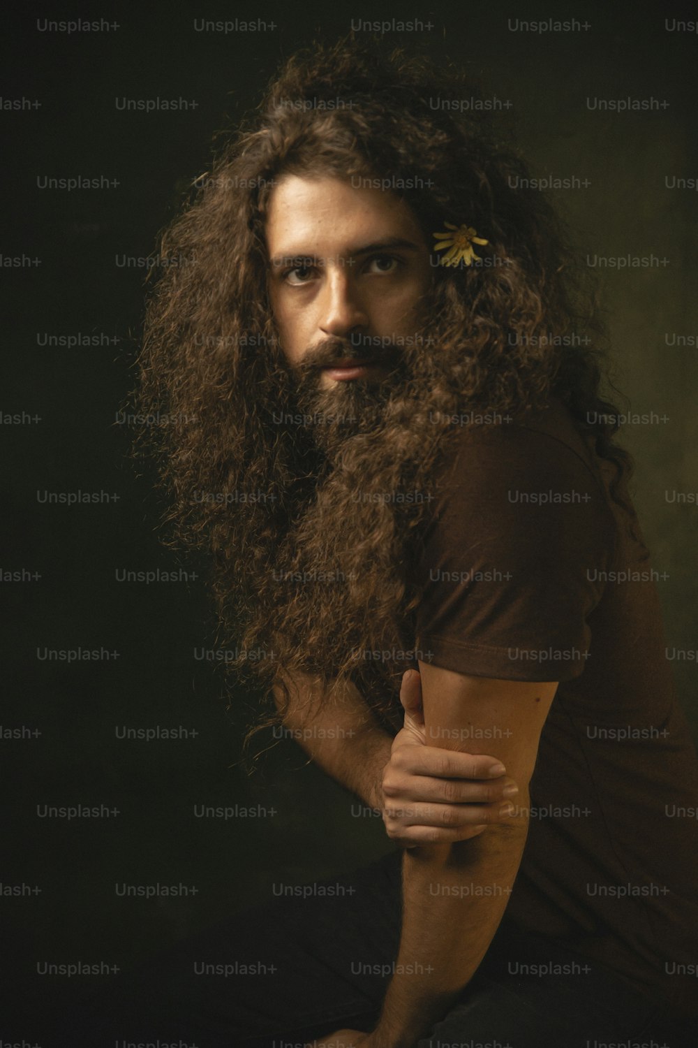 Un hombre con una larga barba y una flor en el pelo