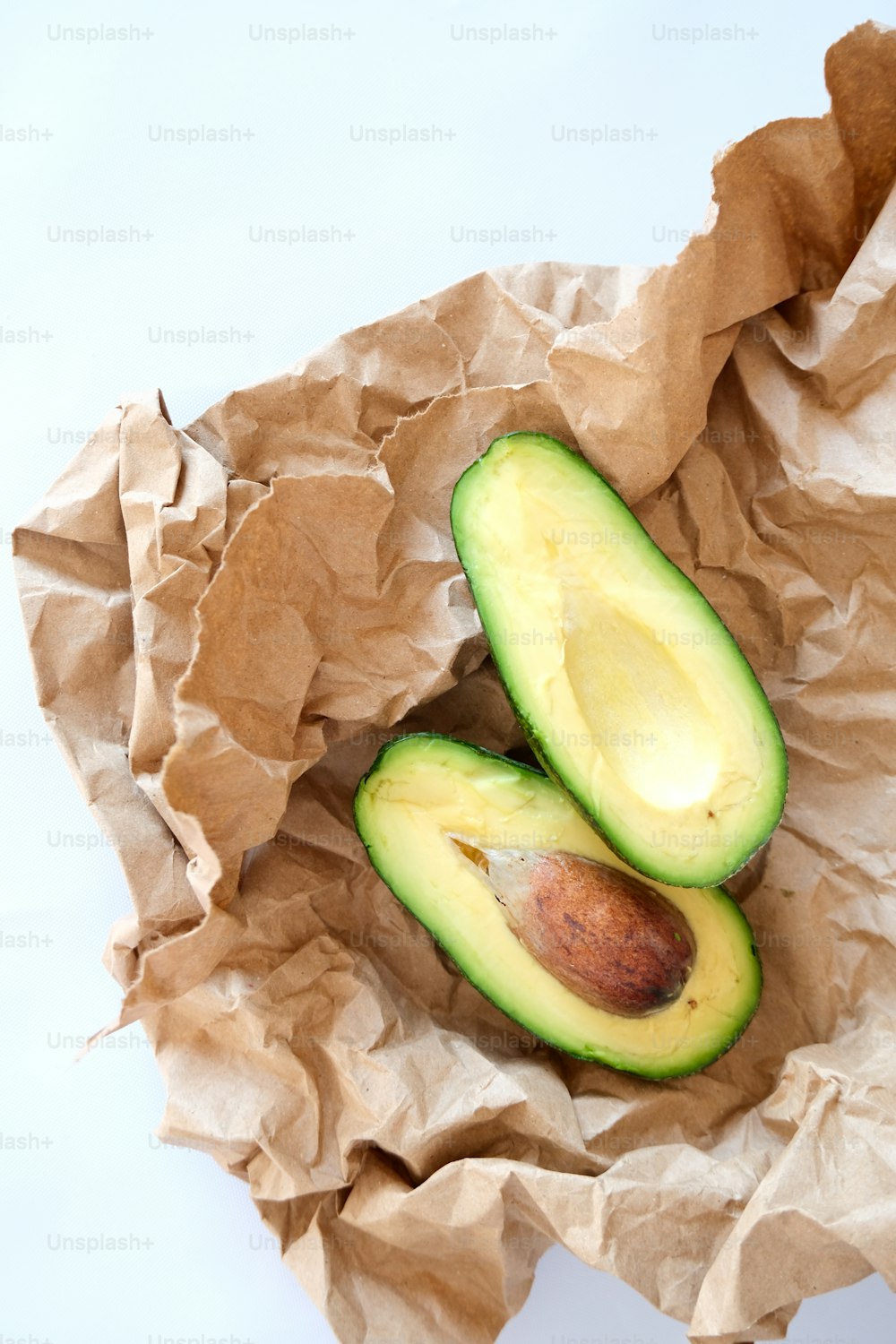 an avocado cut in half on a piece of brown paper