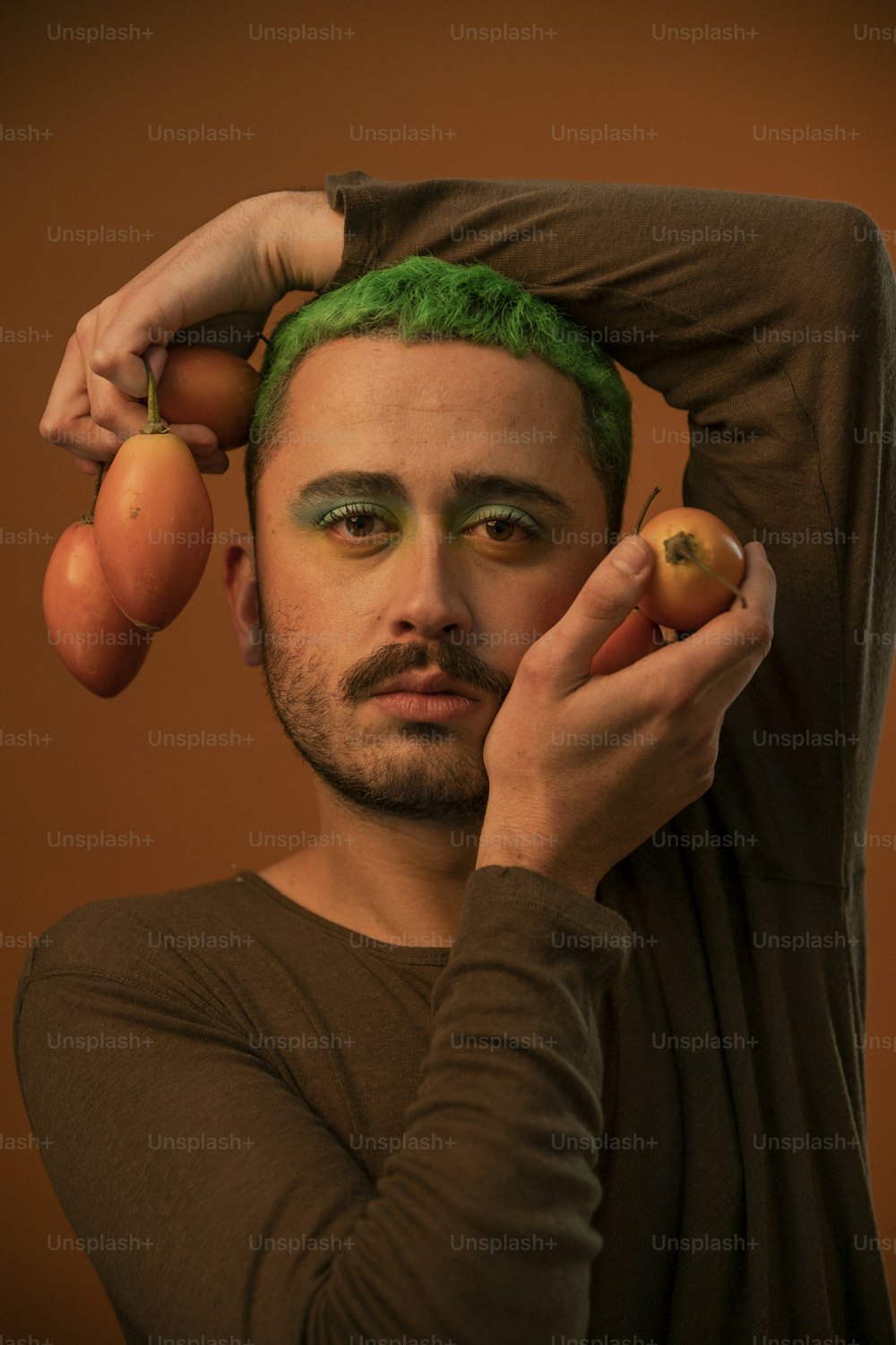 a man with green hair holding two peaches