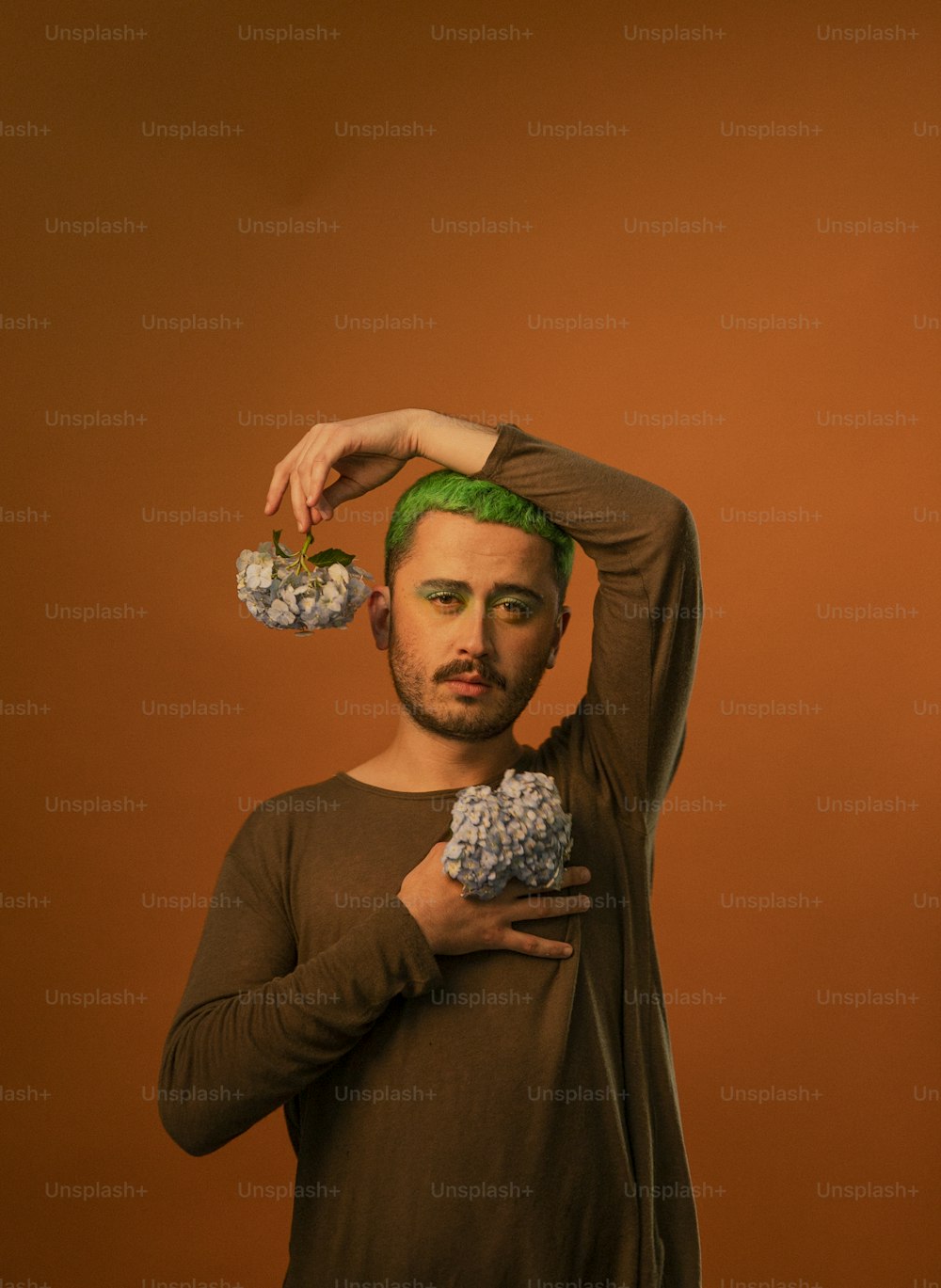 Un hombre con cabello verde sosteniendo una magdalena