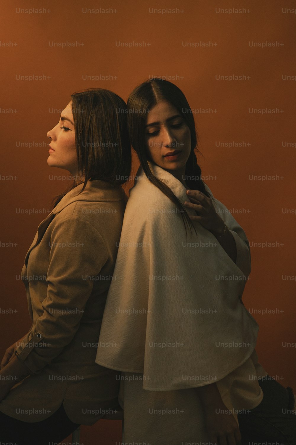 Zwei Frauen stehen nebeneinander vor einer orangefarbenen Wand
