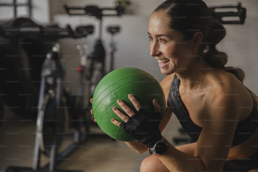 Una mujer sosteniendo una pelota verde en un gimnasio