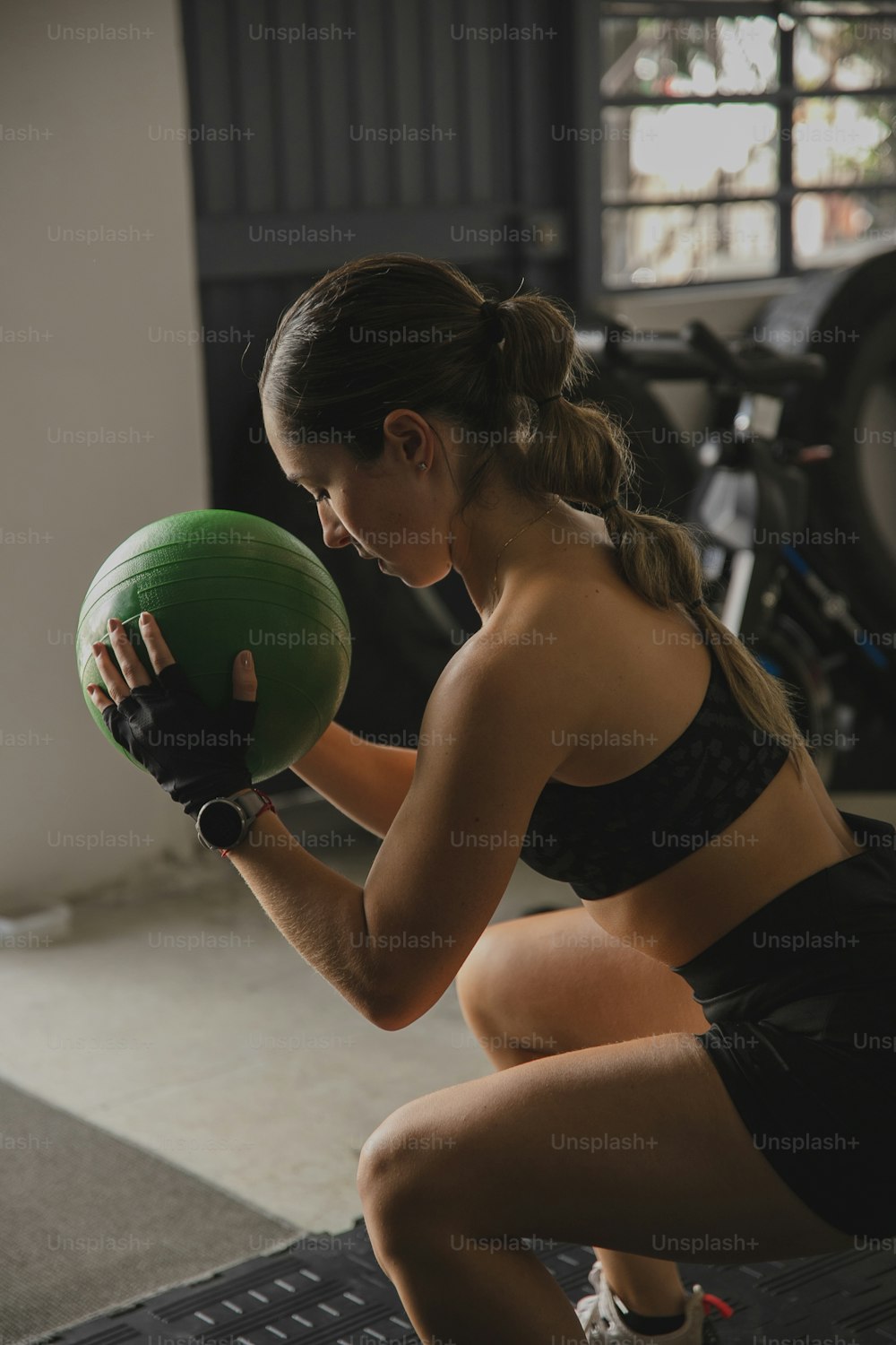 a woman squatting down holding a green ball