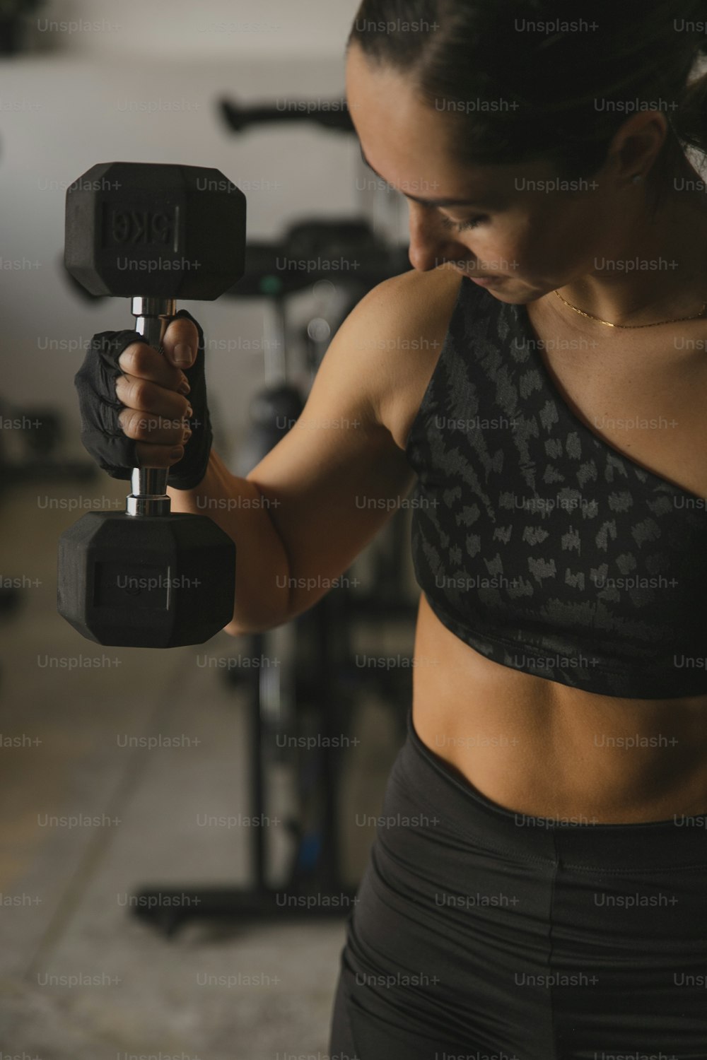 a woman holding a pair of dumbs in a gym