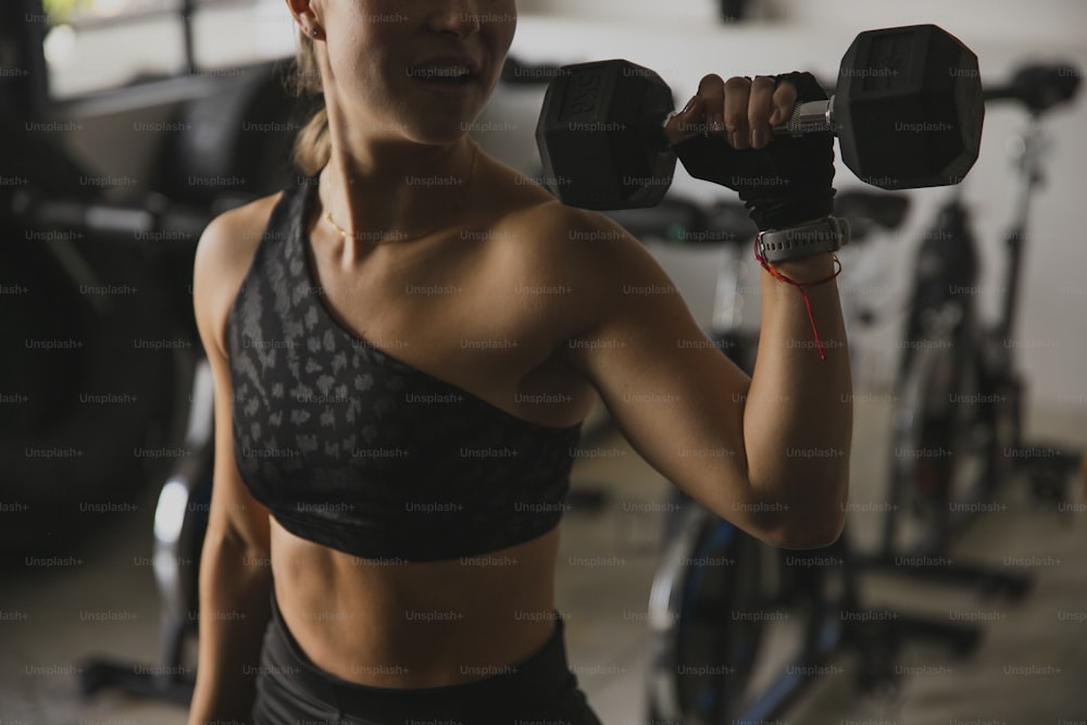 a woman holding a pair of dumbs in a gym