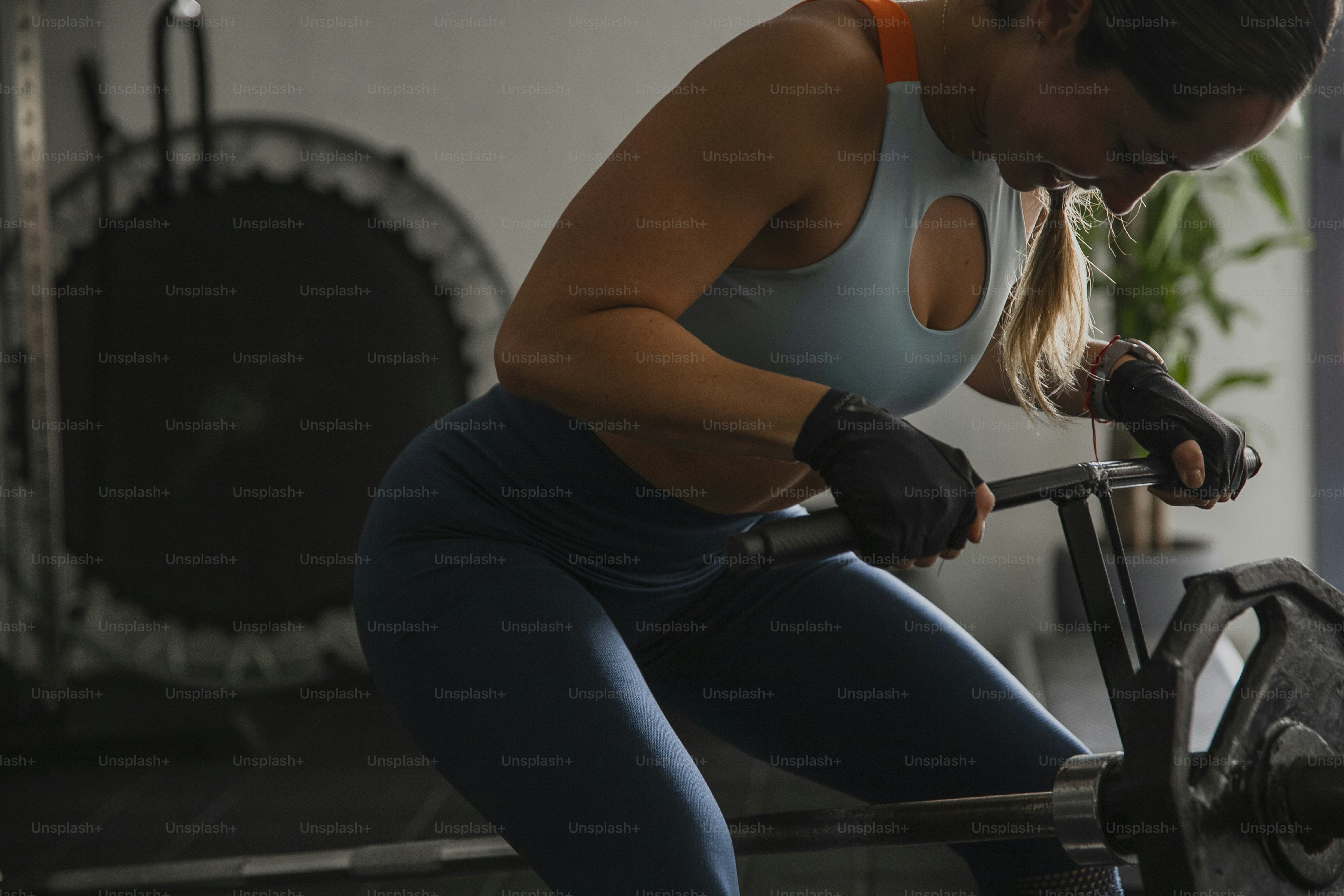 uma mulher que se exercita com uma barra em um ginásio